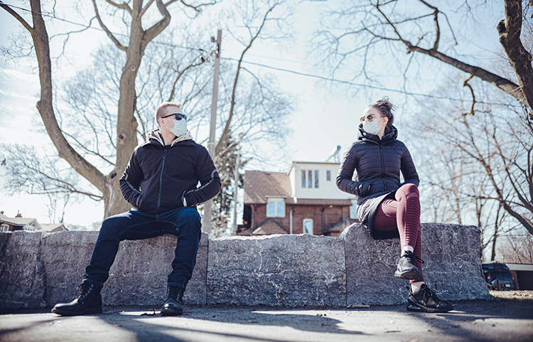 Man and woman socially distancing outside a house